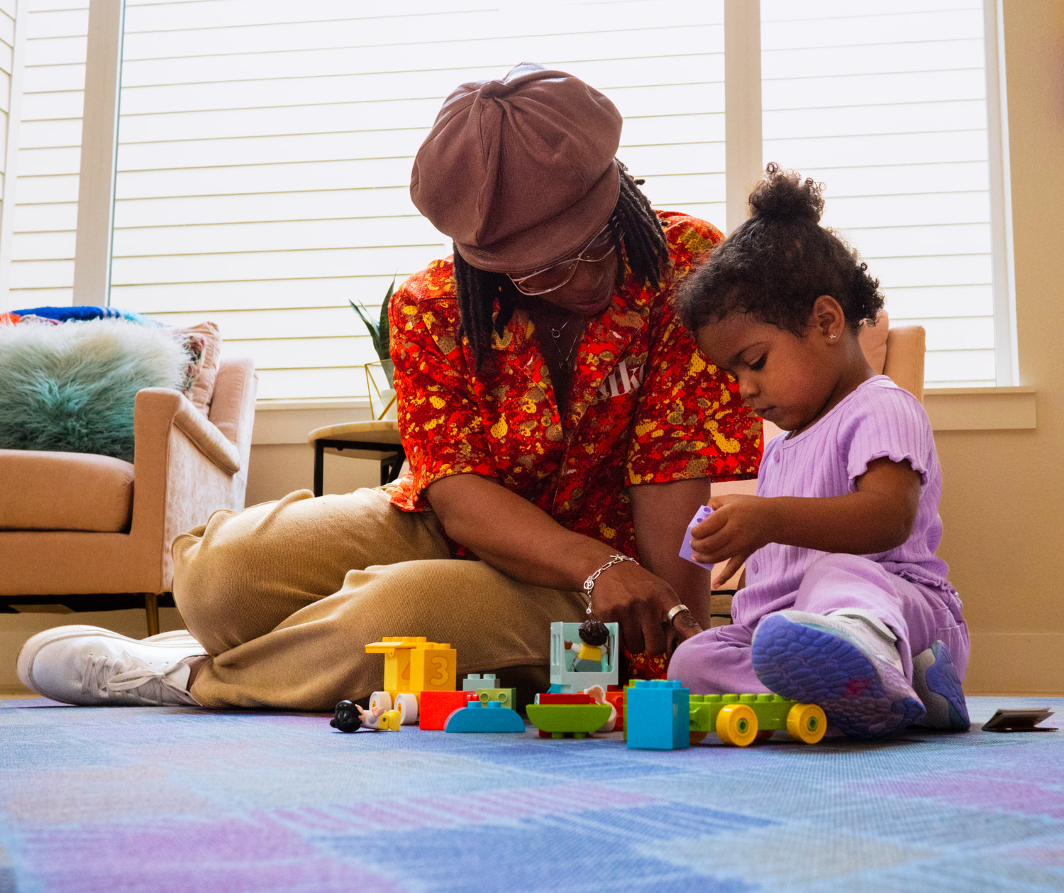 Parent and toddler building toys on Swankymat blue purple exercise mat and play mat in bright living room.