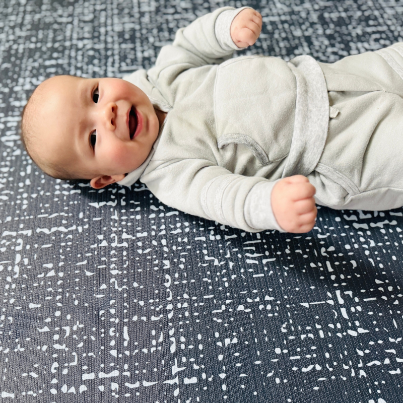 Happy baby lying on Swankymat blue white textured exercise mat and play mat. Safe non-toxic mat for babies.