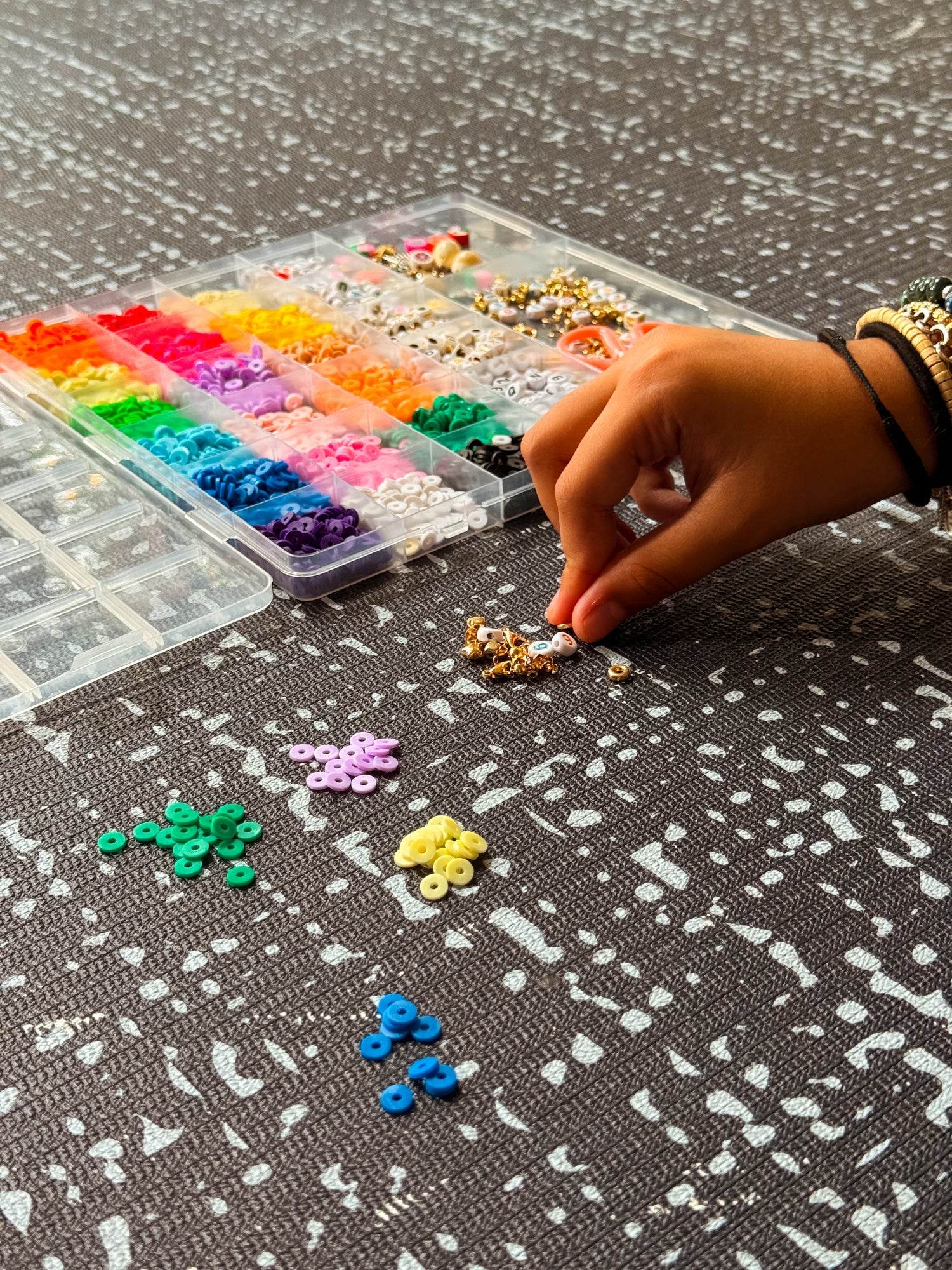 Child sorting colorful beads on Swankymat black white exercise mat and play mat for crafts and play.
