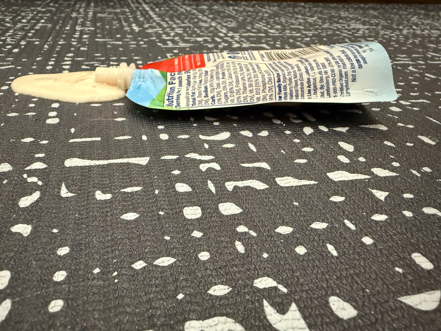 Spilled baby food pouch on Swankymat cushioned black white textured play mat showing easy wipe clean surface.