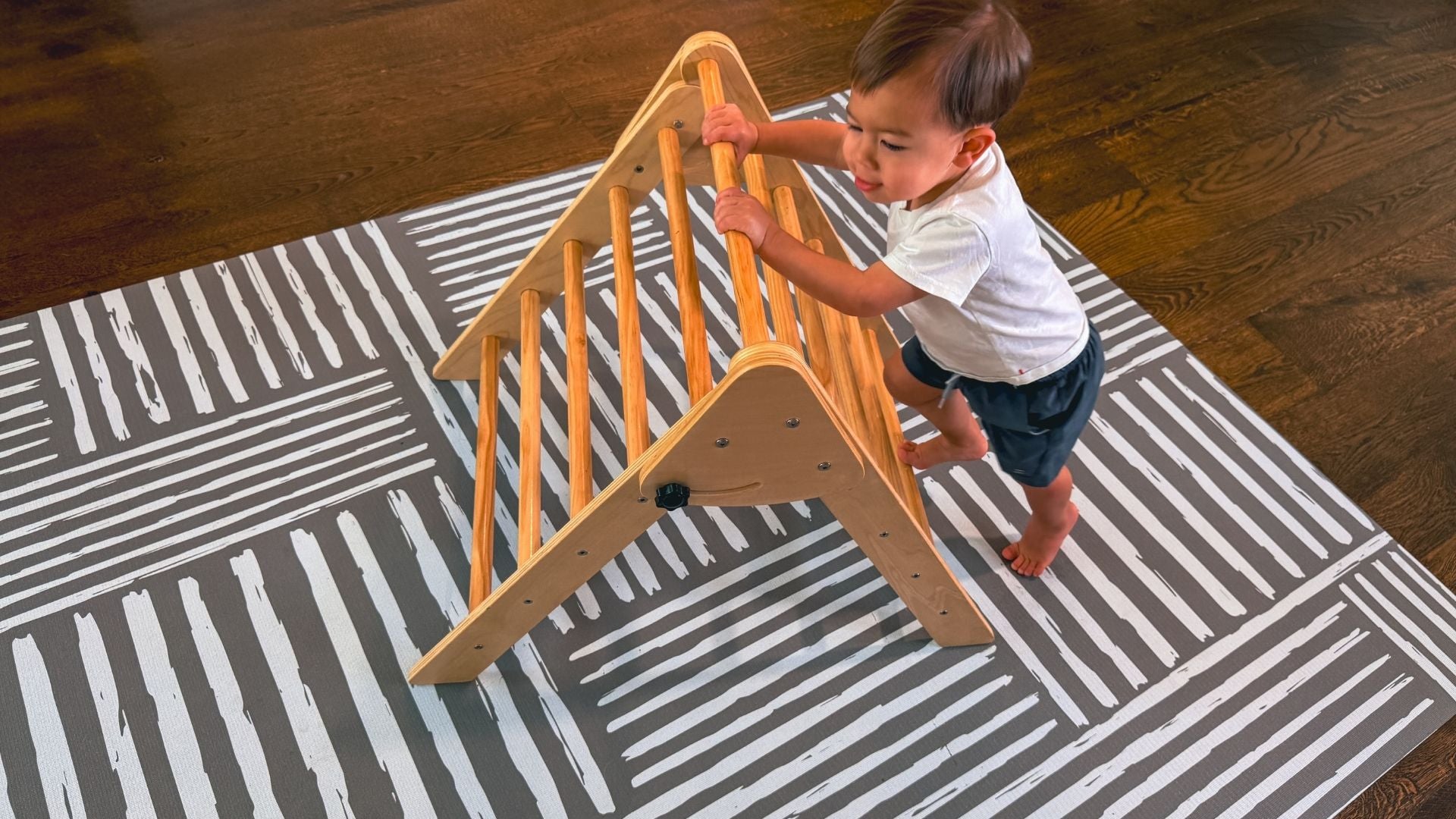Toddler climbing on play set over Swankymat striped foam play mat