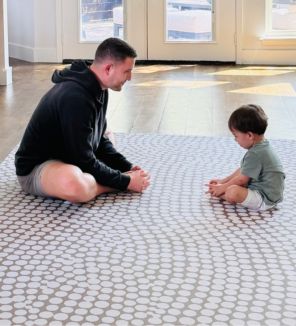 Father and child playing together on Circa Sandstone non-toxic extra large exercise and play mat in a modern living room with natural light
