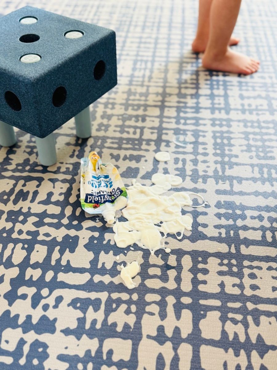 Sloane Navy non-toxic yoga mat and  baby play mat with spilled yogurt, showing easy-to-clean waterproof surface.