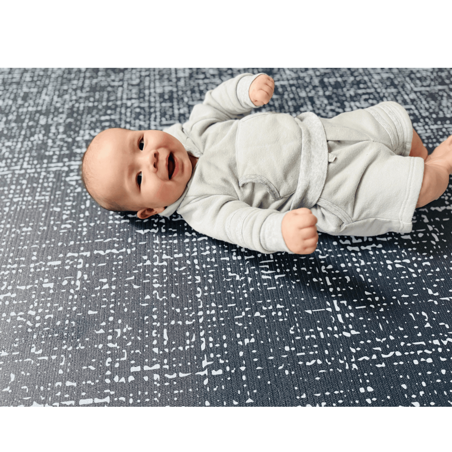 Happy baby laying on Swankymat Speckle Navy non-toxic eco-friendly extra large exercise mat and play mat, safe and cushioned for tummy time and play